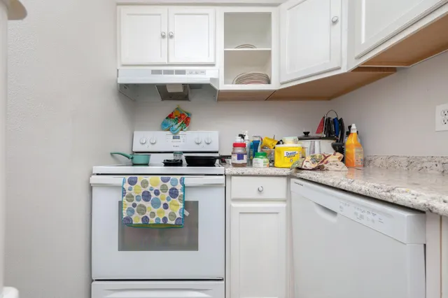 a kitchen with stainless steel appliances granite countertop a lot of cabinets and a wooden floor