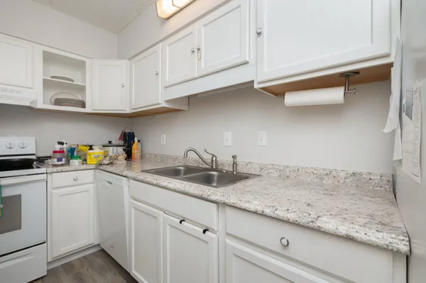 a kitchen with granite countertop white cabinets and white appliances
