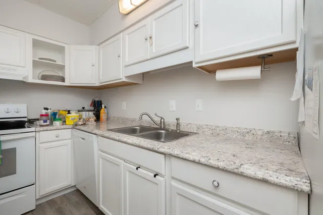 a kitchen with granite countertop white cabinets and white appliances