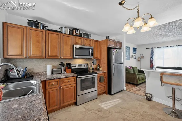 a kitchen with stainless steel appliances granite countertop a refrigerator a stove a sink dishwasher a dining table and chairs with wooden floor