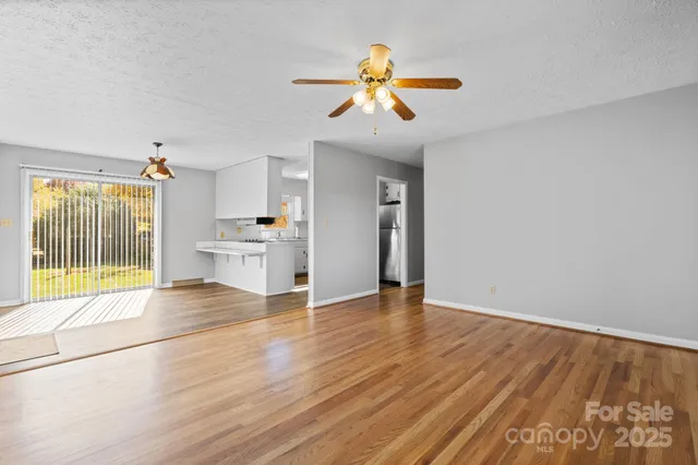 a view of an empty room with window and wooden floor