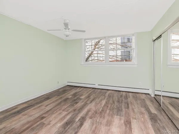 an empty room with wooden floor chandelier fan and windows