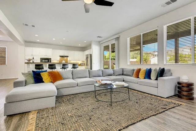 a kitchen with stainless steel appliances granite countertop a stove top oven a sink a refrigerator with white cabinets and wooden floor