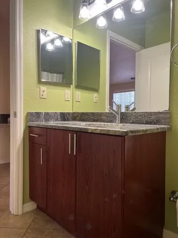 a bathroom with a granite countertop sink toilet and a mirror