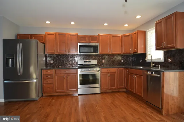 a kitchen with stainless steel appliances wooden cabinets and a stove top oven