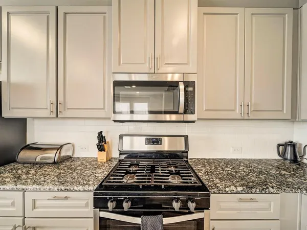 a kitchen with granite countertop white cabinets and stainless steel appliances