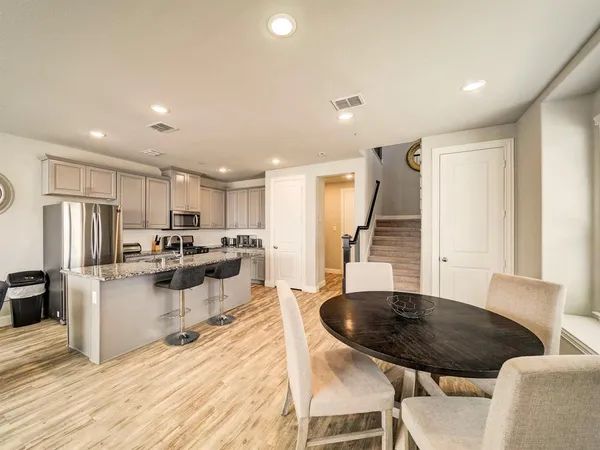 a kitchen with stainless steel appliances kitchen island granite countertop a sink a stove a refrigerator with white cabinets and wooden floor