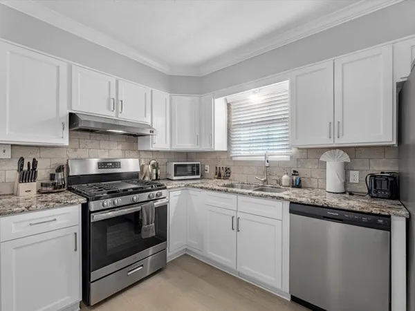 a kitchen with granite countertop white cabinets and white stainless steel appliances