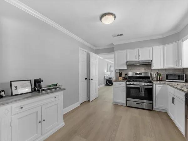 a kitchen with stainless steel appliances a stove a sink and white cabinets