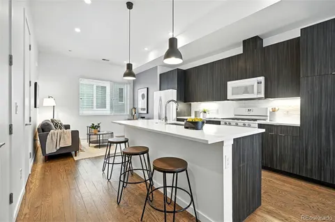 a kitchen with stainless steel appliances granite countertop a stove a sink dishwasher and a refrigerator with wooden floor