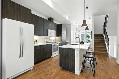 a kitchen with kitchen island wooden cabinets a refrigerator a sink a stove and a wooden floors