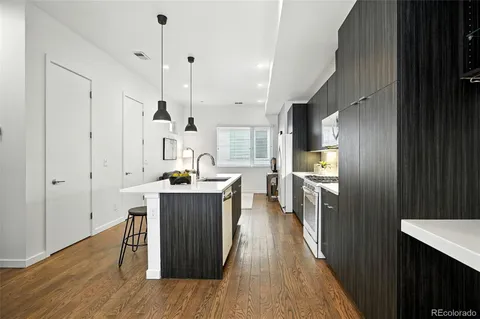 a kitchen with kitchen island granite countertop wooden floors and white cabinets