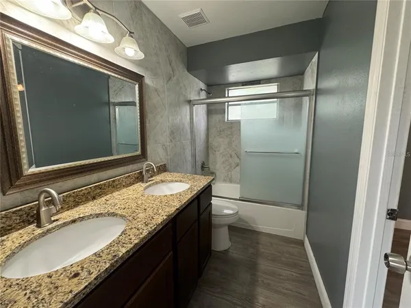 a bathroom with a granite countertop sink toilet and shower