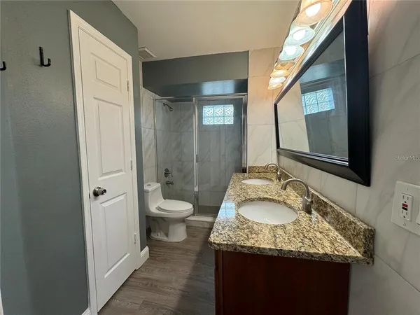 a bathroom with a granite countertop sink and mirror with toilet