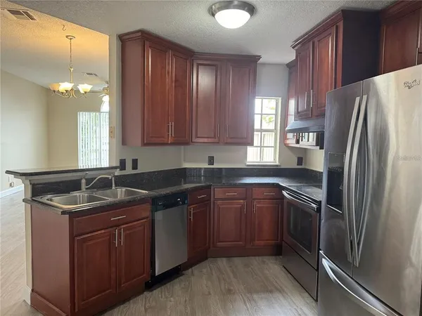 a kitchen with stainless steel appliances granite countertop a sink stove and refrigerator