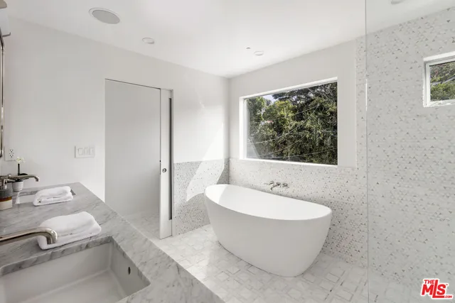 a bathroom with a white tub a vanity and a window
