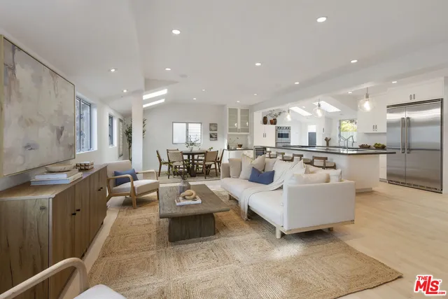 a living room with furniture kitchen view and a chandelier