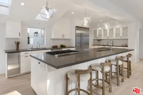 a kitchen with stainless steel appliances granite countertop a sink a stove a refrigerator and island