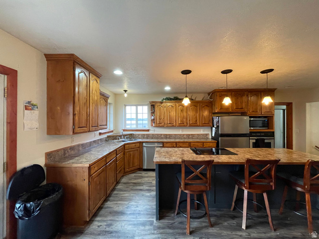 333 Lago Liberty Road Grace, ID 83241 - Photo 30 of 35 Kitchen with wood finish cabinets, a kitchen breakfast bar, a kitchen island with sink, and stainless steel appliances
