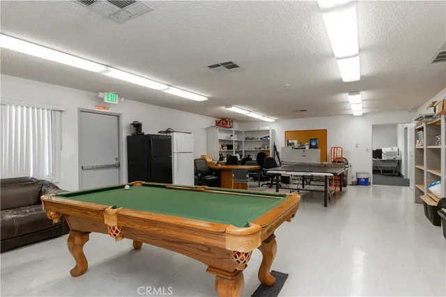 a living room with furniture pool table and a refrigerator