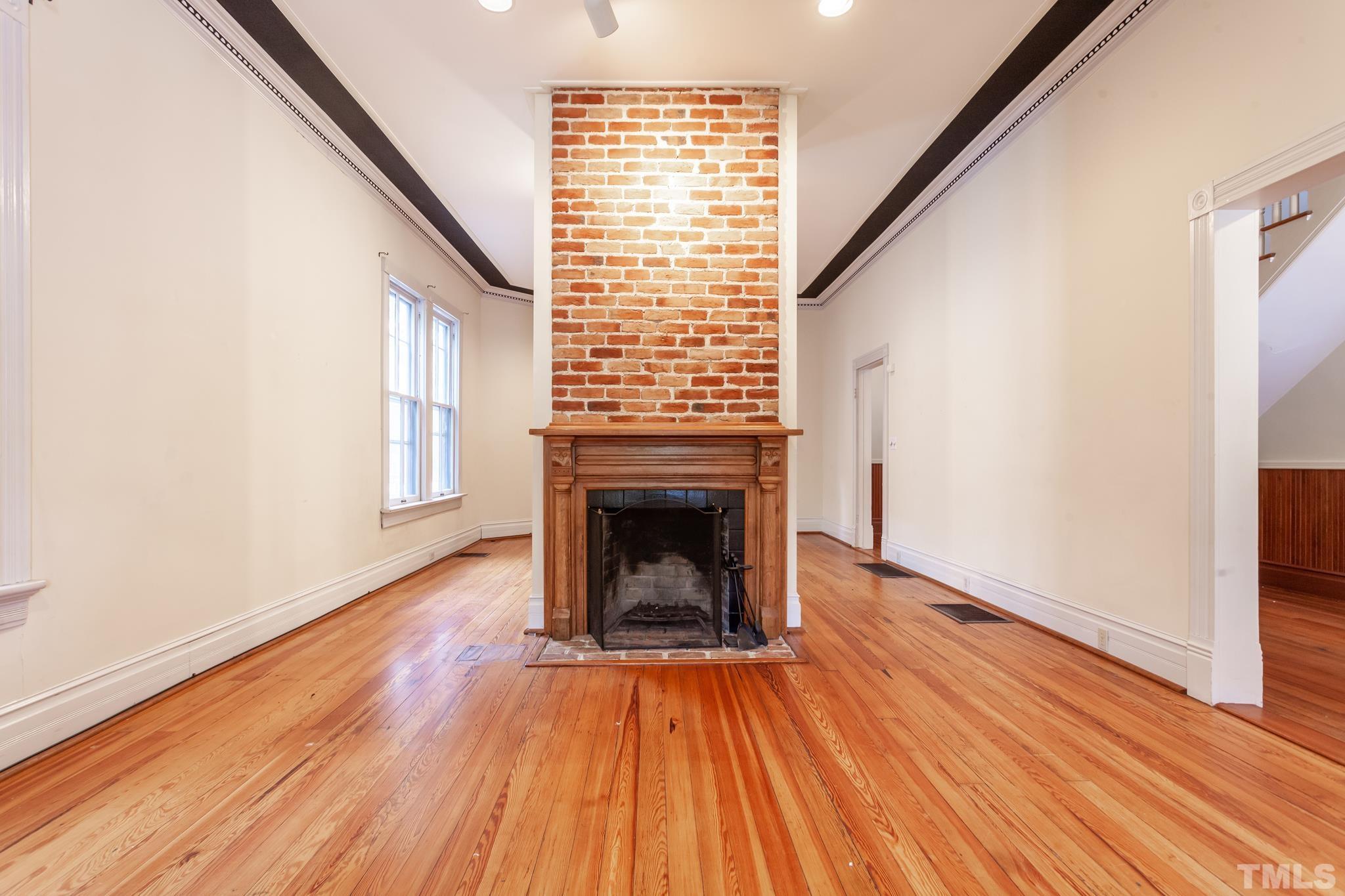 323 East Lane Street Raleigh, NC 27601 - Photo 13 of 42 a view of an empty room with wooden floor fireplace and a window