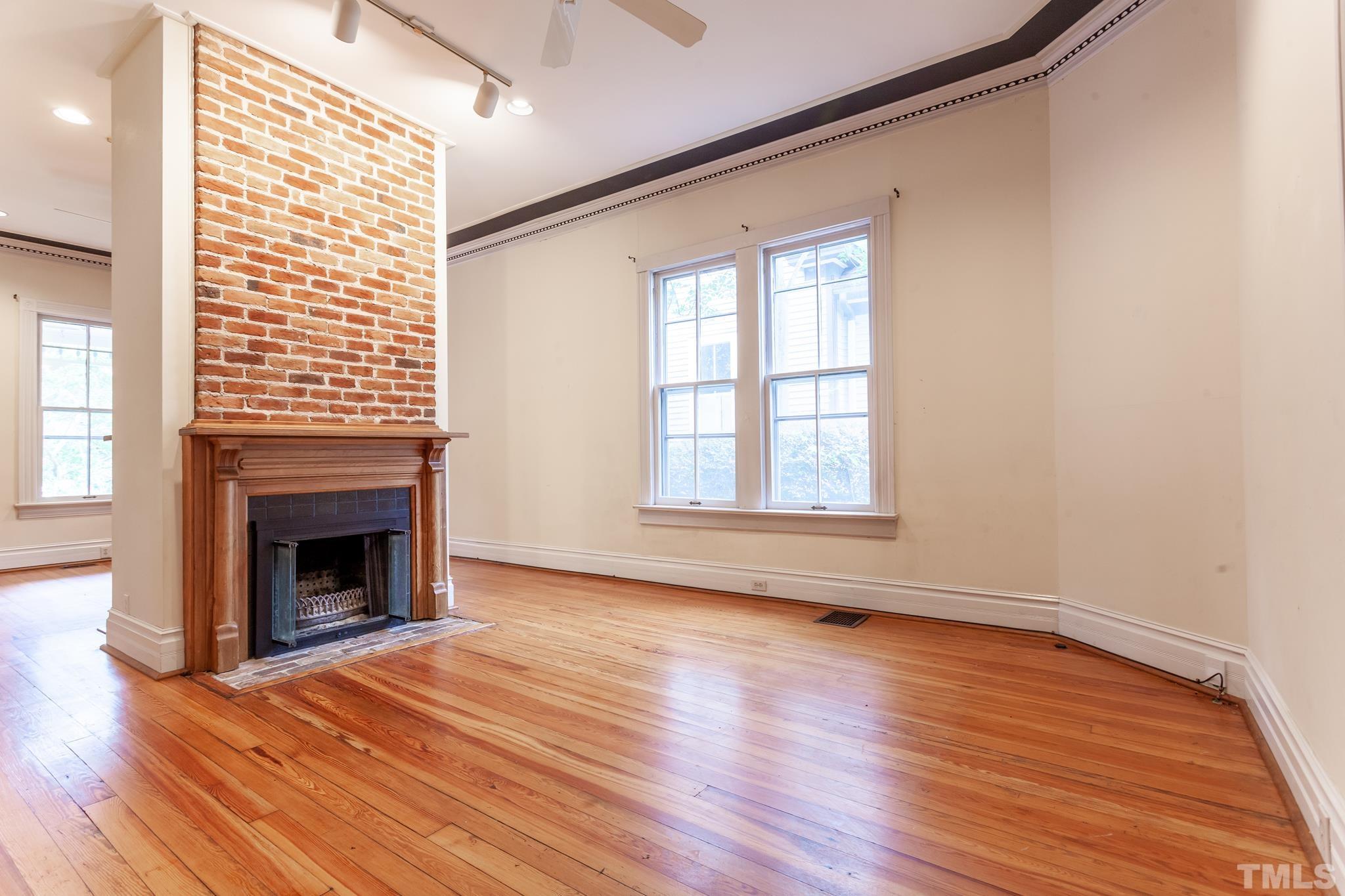 323 East Lane Street Raleigh, NC 27601 - Photo 16 of 42 an empty room with wooden floor fireplace and windows