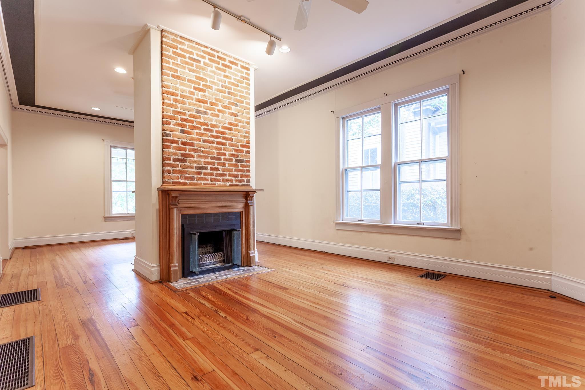 323 East Lane Street Raleigh, NC 27601 - Photo 17 of 42 an empty room with wooden floor fireplace and windows