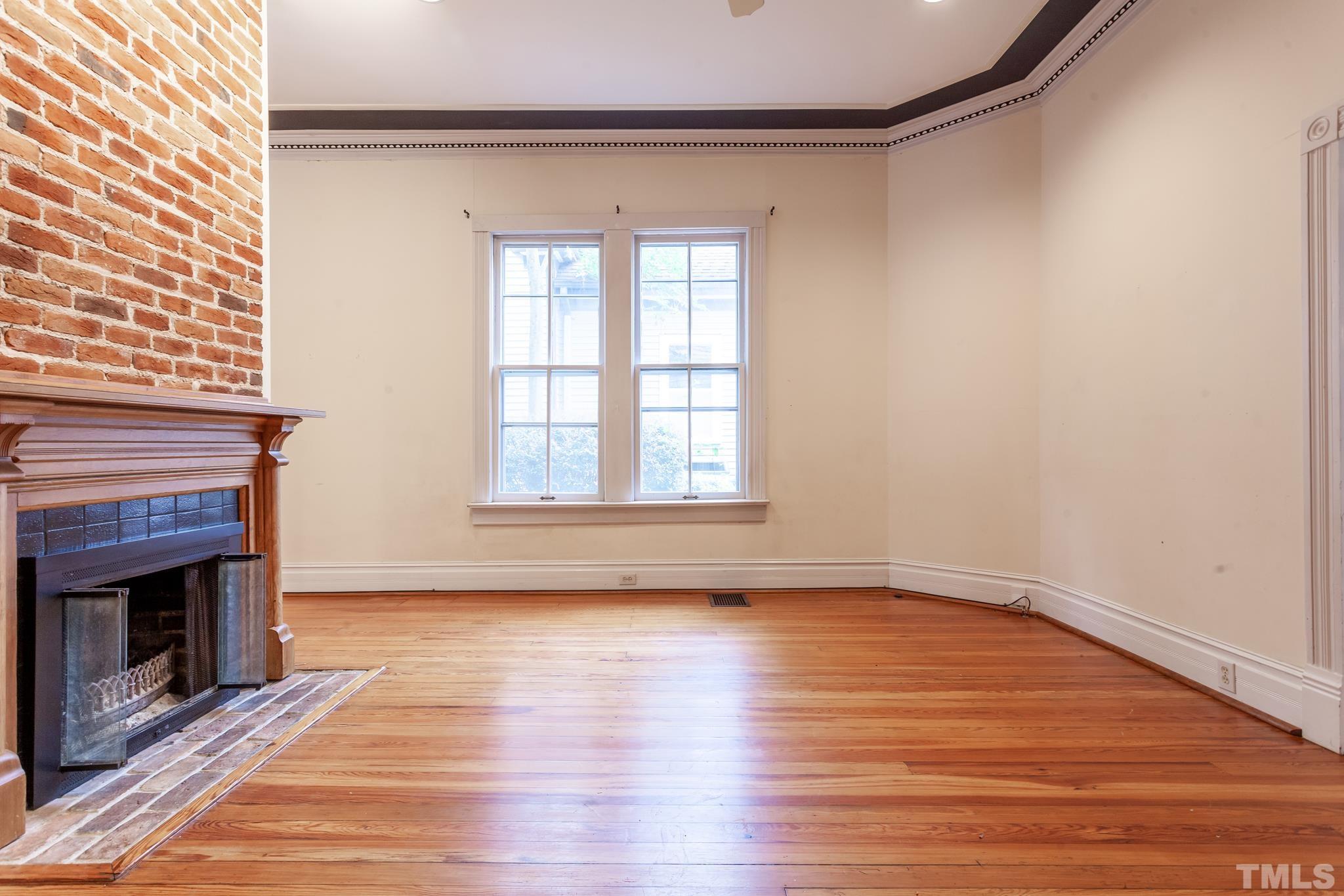 323 East Lane Street Raleigh, NC 27601 - Photo 18 of 42 an empty room with wooden floor fireplace and windows
