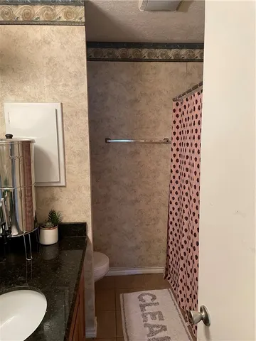 a bathroom with a granite countertop shower a sink and a toilet