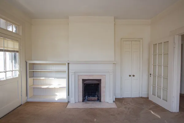 an empty room with windows and fireplace