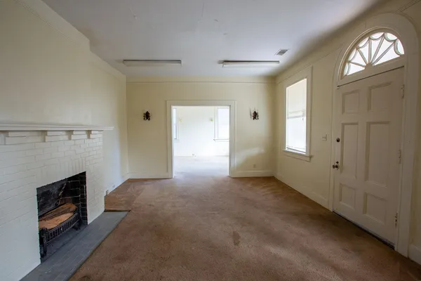 an empty room with windows and fireplace