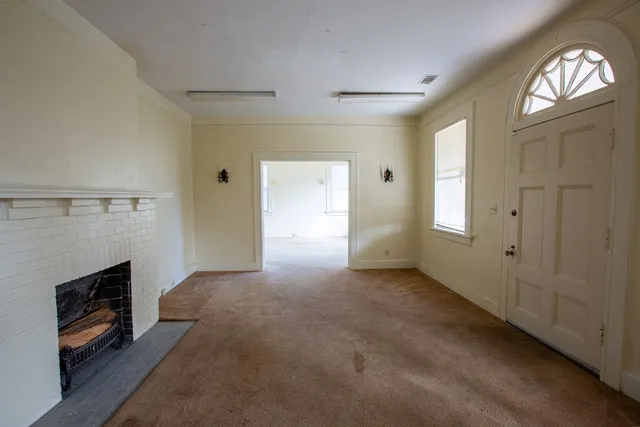 an empty room with windows and fireplace