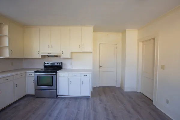 a kitchen with granite countertop white cabinets and a wooden floor