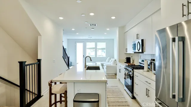 a kitchen with stainless steel appliances granite countertop a refrigerator a stove a sink dishwasher and a refrigerator with wooden floor