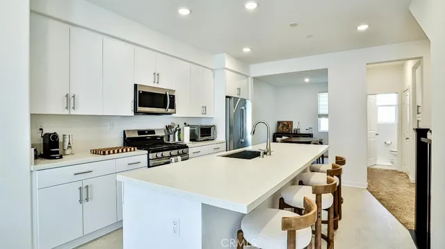 a kitchen with stainless steel appliances a stove a sink a microwave a refrigerator and cabinets