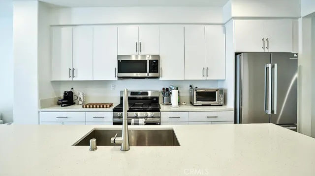 a kitchen with granite countertop a refrigerator stove and microwave