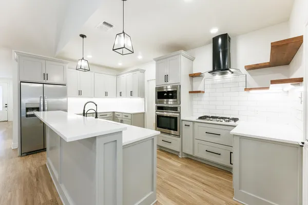 a kitchen with stainless steel appliances kitchen island granite countertop a sink a stove and a refrigerator