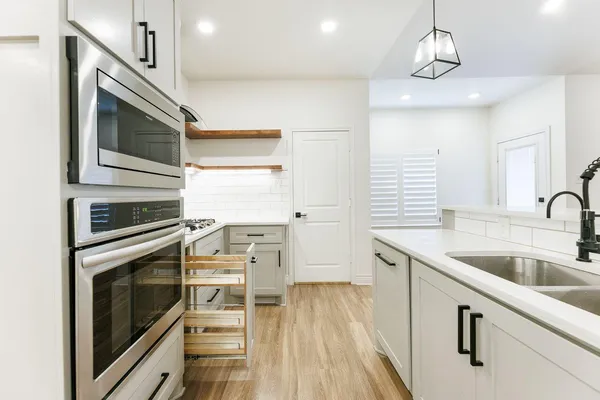 a kitchen with stainless steel appliances white cabinets and wooden floor