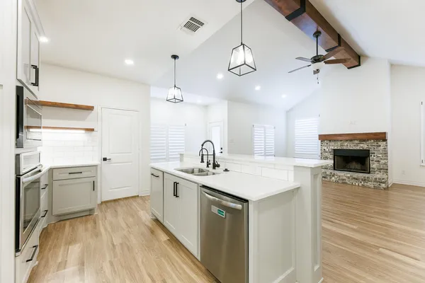 a large kitchen with granite countertop a sink dishwasher a stove and a refrigerator with wooden floor