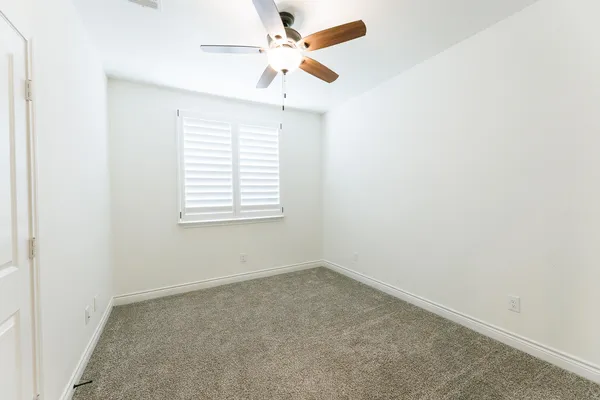 an empty room with a window and a fan