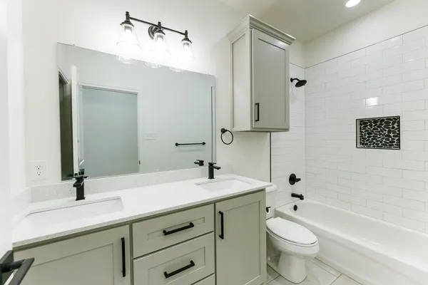 a bathroom with a double vanity sink toilet mirror and bathtub