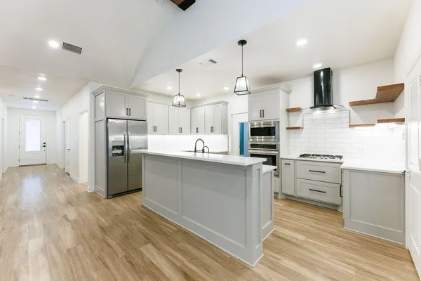 a large kitchen with stainless steel appliances kitchen island a refrigerator and a stove top oven