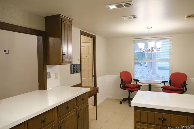 a room with a table chairs and a refrigerator