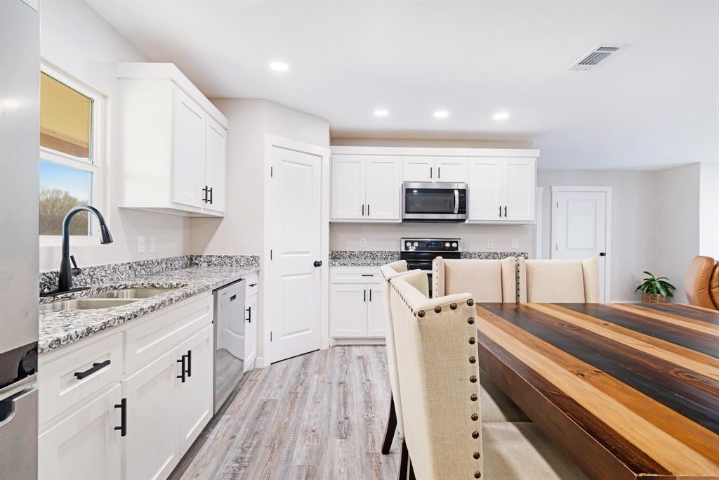 600 Private Road Brookston, TX 75421 - Photo 7 of 26 a kitchen with stainless steel appliances granite countertop a stove top oven a sink dishwasher and a refrigerator with wooden floor