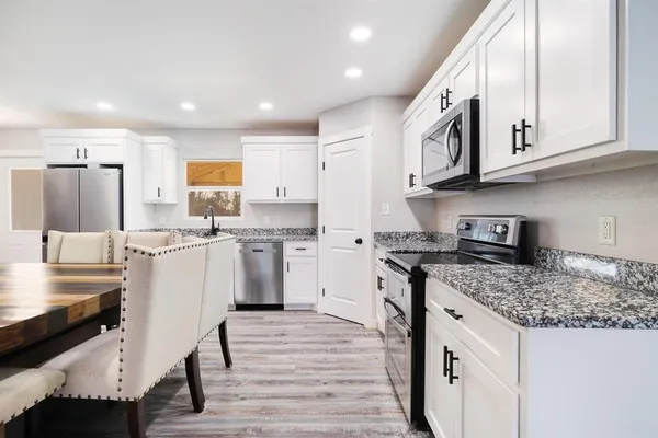 a kitchen with stainless steel appliances granite countertop a white cabinets and wooden floor