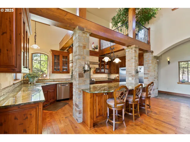 a dining room with stainless steel appliances kitchen island granite countertop a table chairs and a view of living room