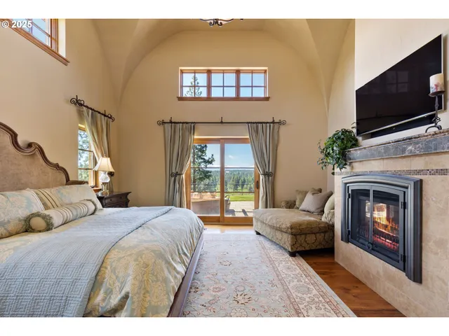 a bedroom with a bed a flat screen tv and a fireplace