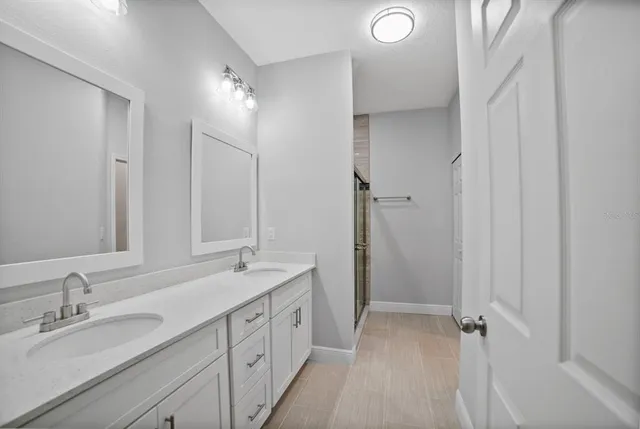 a spacious bathroom with a double vanity sink a mirror and a shower