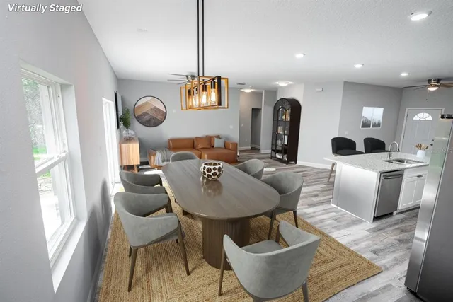 a living room with couches a dining table and chairs with wooden floor