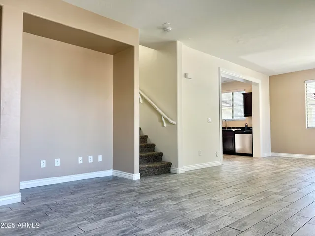 a view of a big room with wooden floor and a kitchen